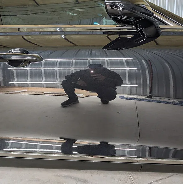 Detailer reflected in freshly coated paint at the Detail Now studio